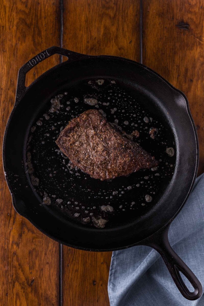 The round steak seared to a deep brown crust in the cast iron skillet, ready to come out while the vegetables cook.
