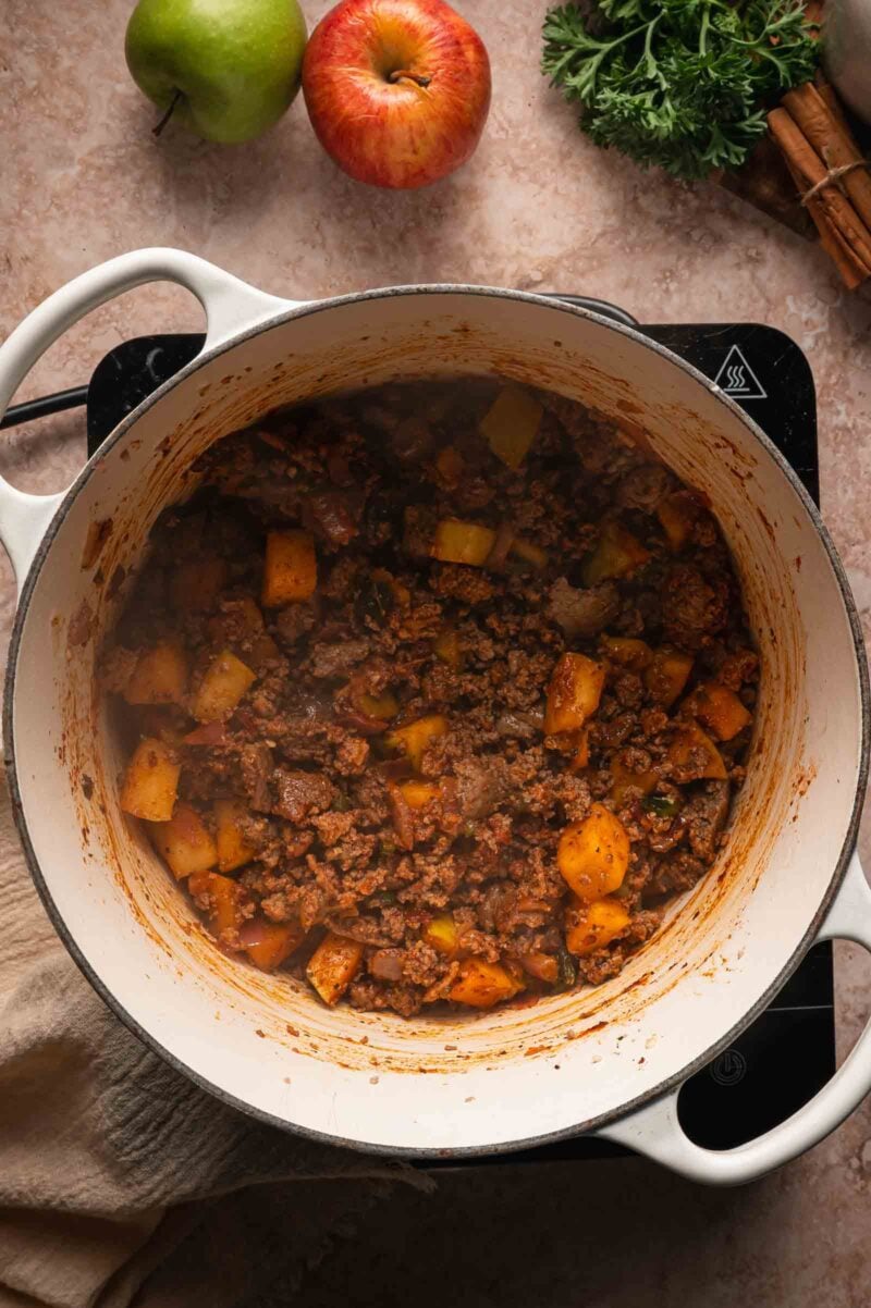 The spices stirred through the ground turkey and apples so everything is coated before the liquid goes in.