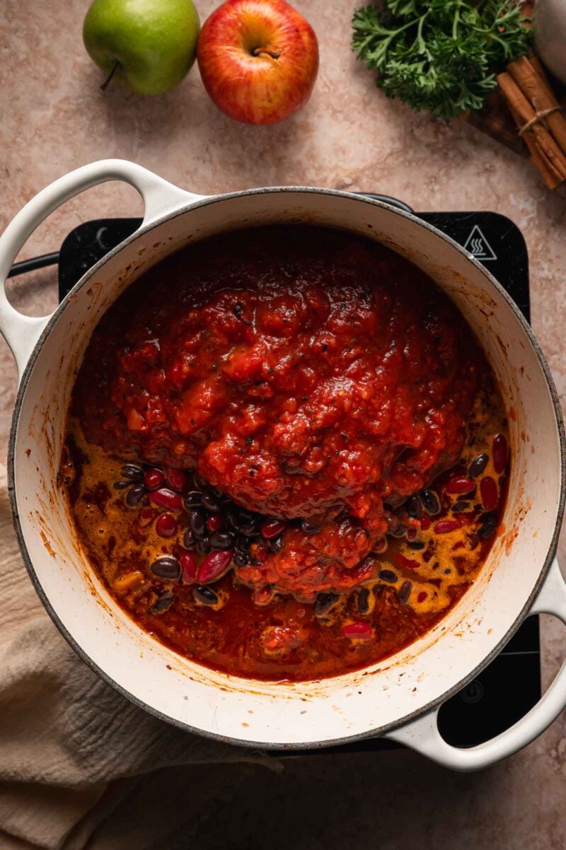 Crushed tomatoes with black and kidney beans added to the simmering turkey apple chili.