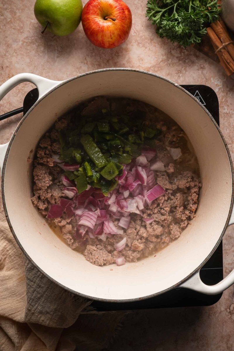 Chopped roasted poblano and diced red onion added to the browned ground turkey in the Dutch oven.