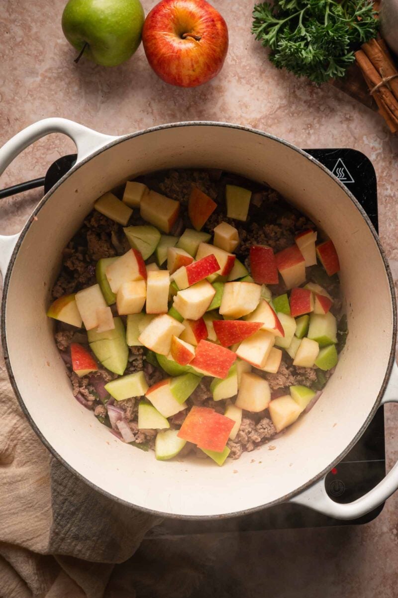 Diced red and green apples added over the browned ground turkey and onion in the Dutch oven.