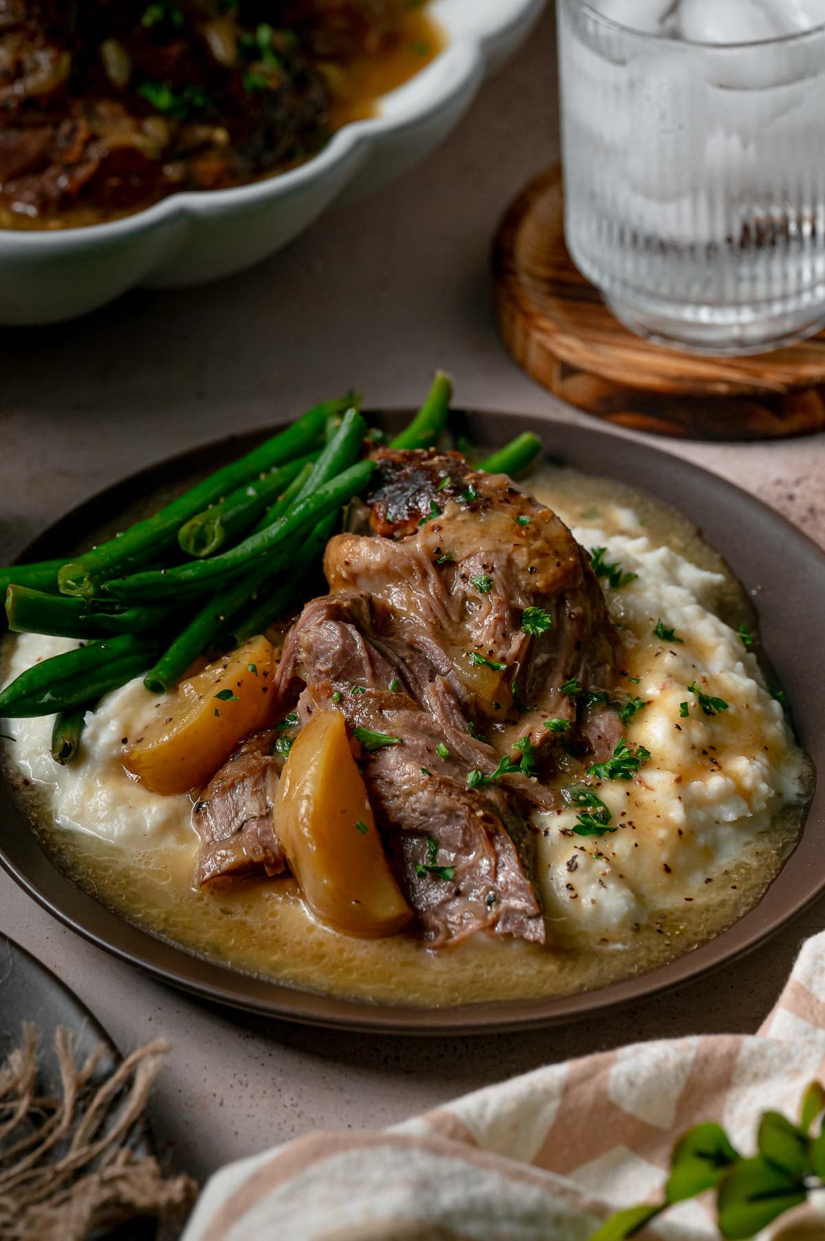 Apple cider braised pork with tender apple wedges and cider gravy over mashed potatoes, served with green beans.