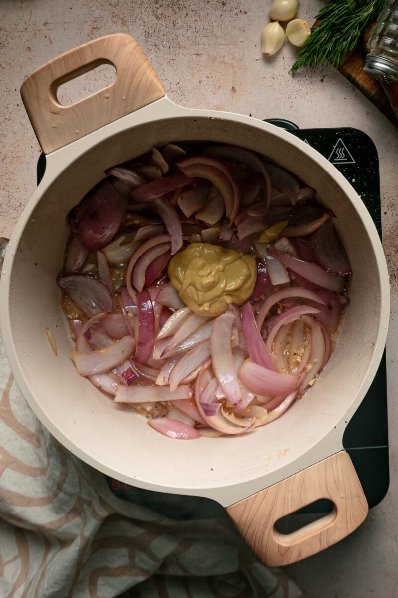 A spoonful of Dijon mustard added to the softened red onions in the Dutch oven.