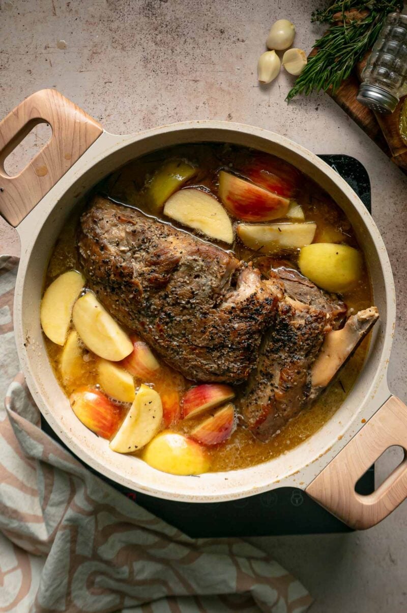Apple wedges added around the braising pork shoulder in the Dutch oven for the last stretch of cooking.