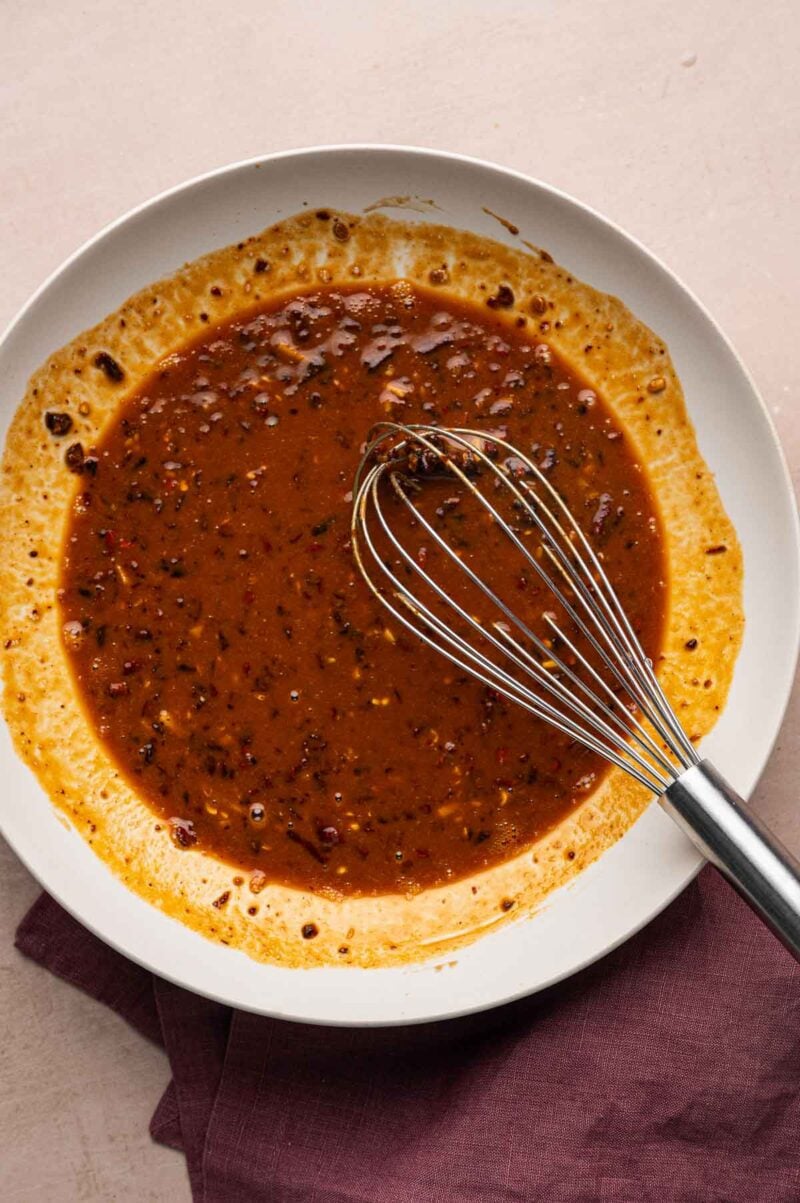 Dan dan sauce whisked smooth into a glossy sesame-chili sauce in a white bowl.
