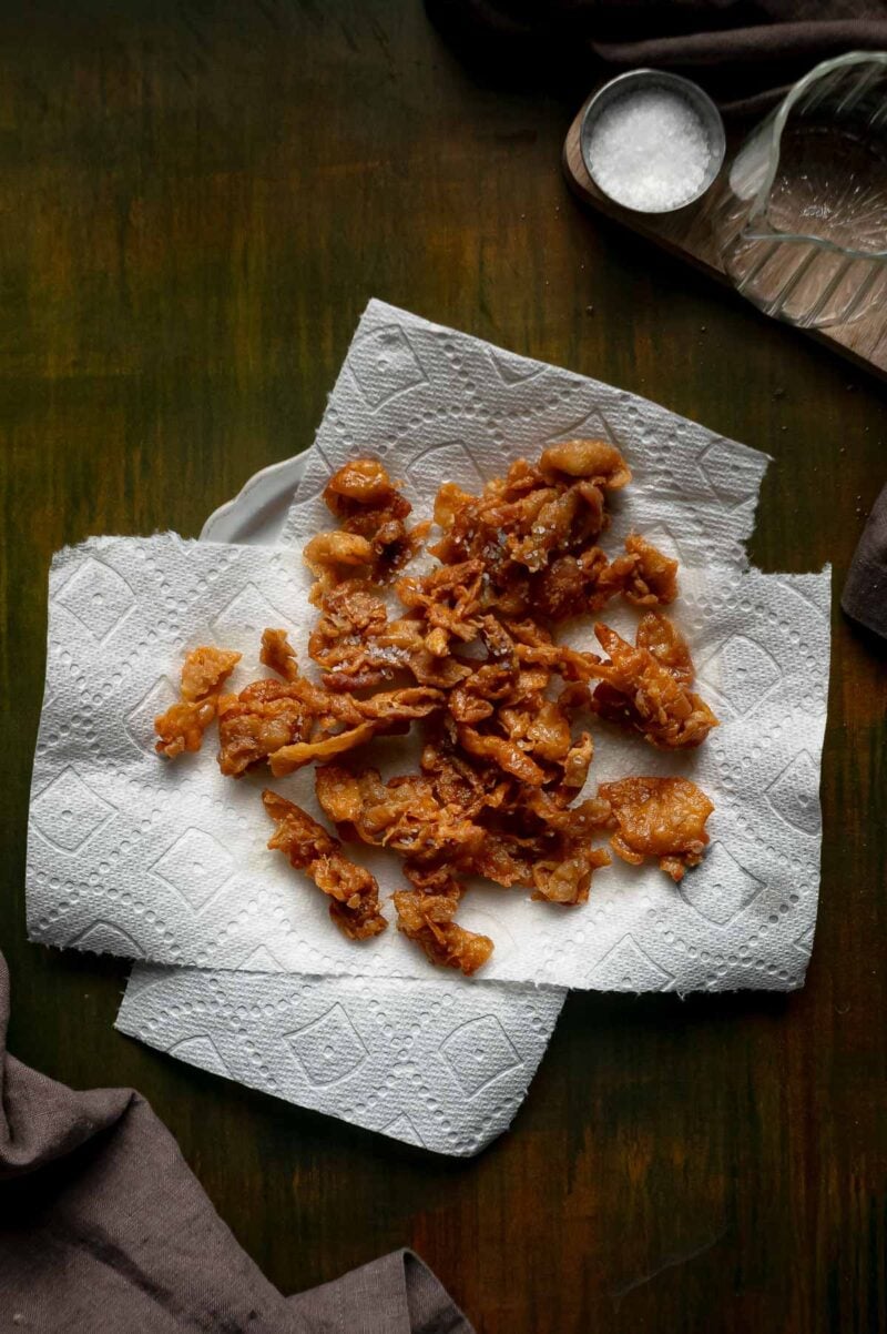 Crispy chicken skin gribenes draining on paper towels after coming out of the hot schmaltz.