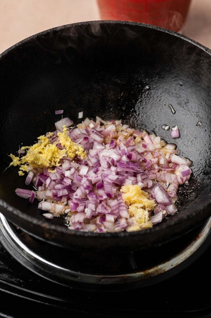 Chopped red onion, grated ginger and garlic in the cast iron skillet to start the curry sauce.