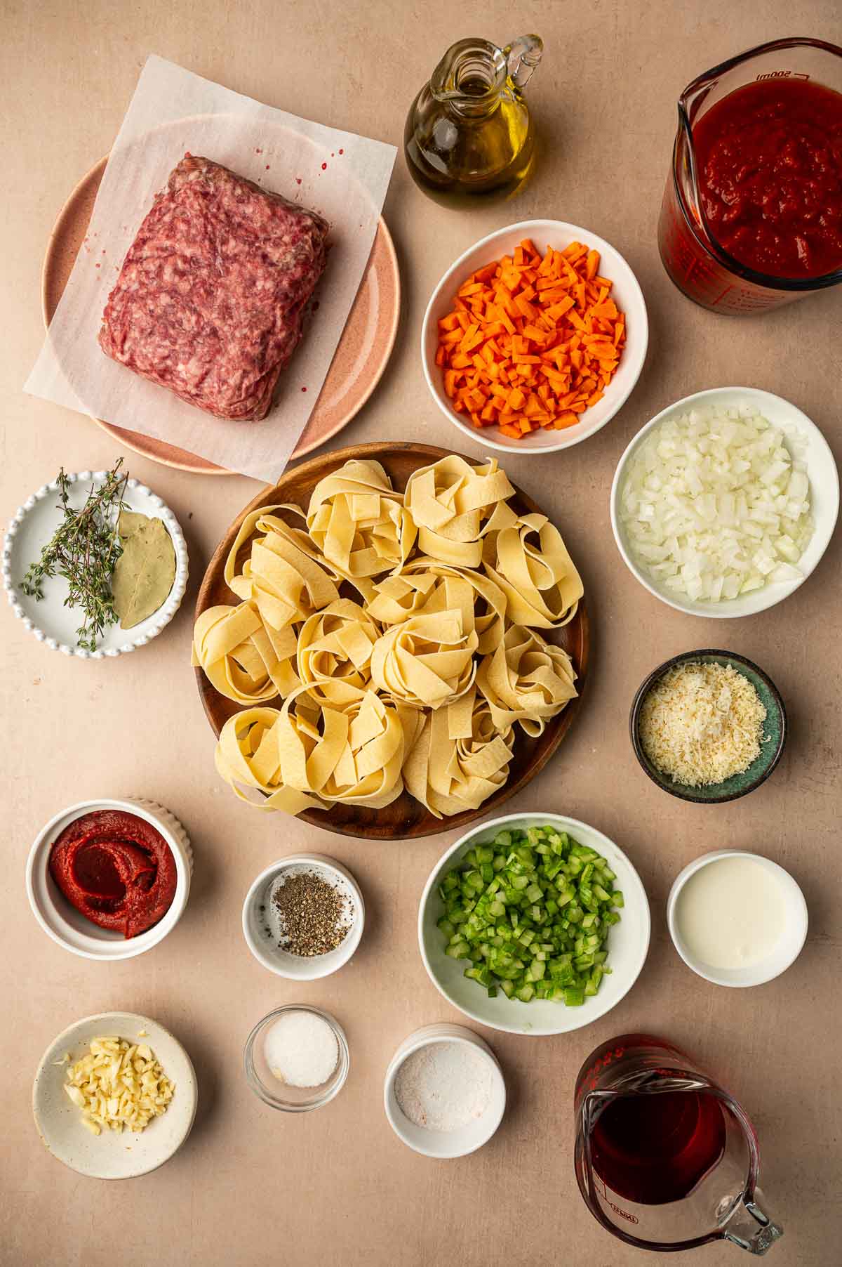 Ingredients for lamb bolognese: ground lamb, pappardelle nests, diced carrots, onion and celery, garlic, tomato paste, crushed tomatoes, red wine, thyme, bay leaves, cream and Parmesan.