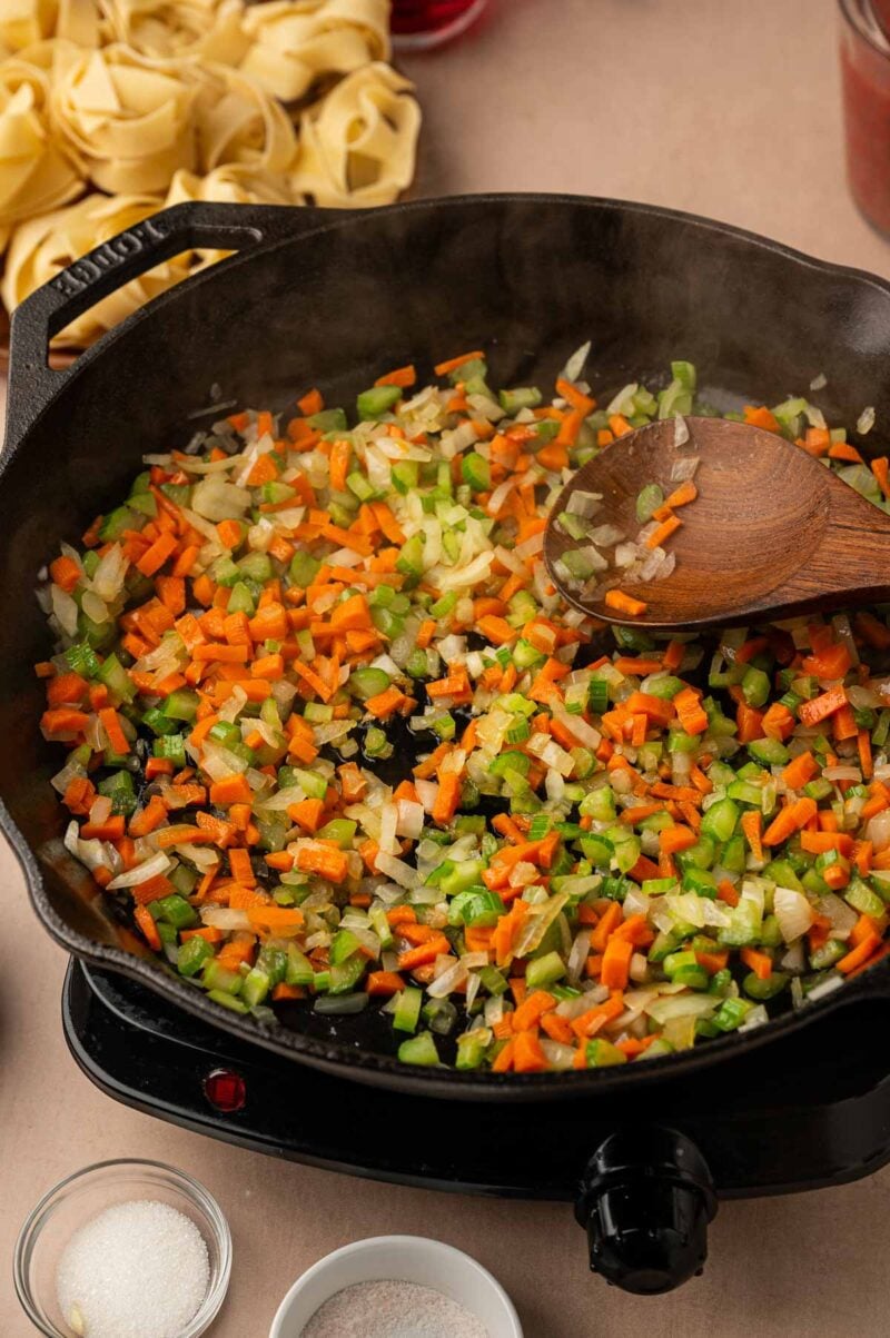Finely diced onion, carrots and celery softening in olive oil in a cast iron skillet, stirred with a wooden spoon.