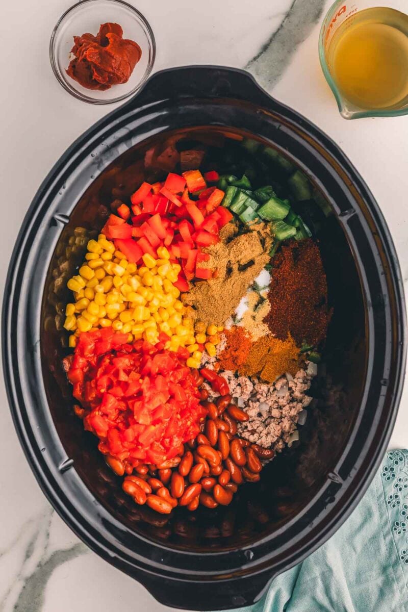 Ground spices sprinkled over the peppers, corn, tomatoes, beans and turkey in the slow cooker before stirring.